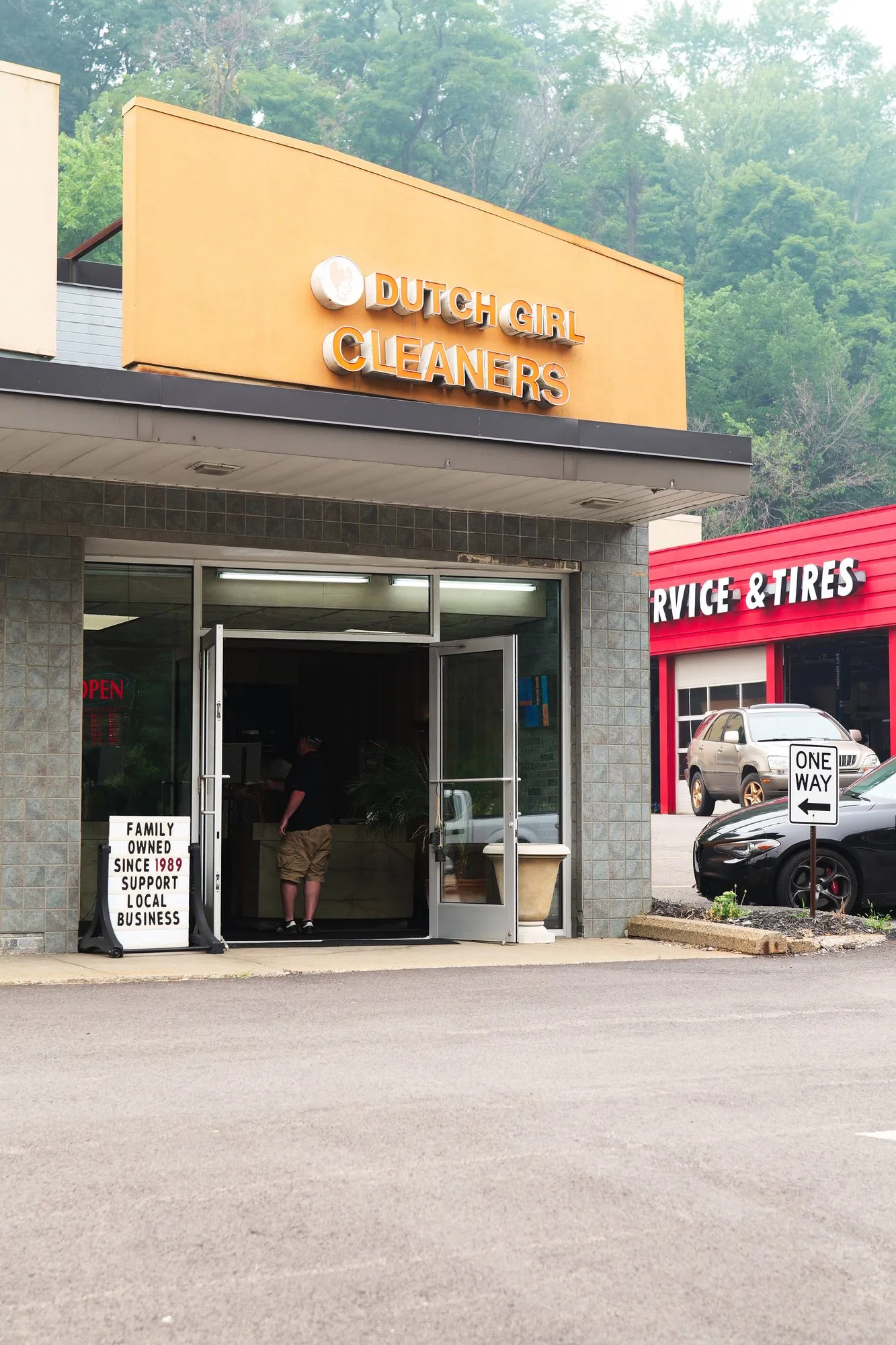 The Dutch Girl Cleaners shopfront seen from the parking lot, with its sign above the door.